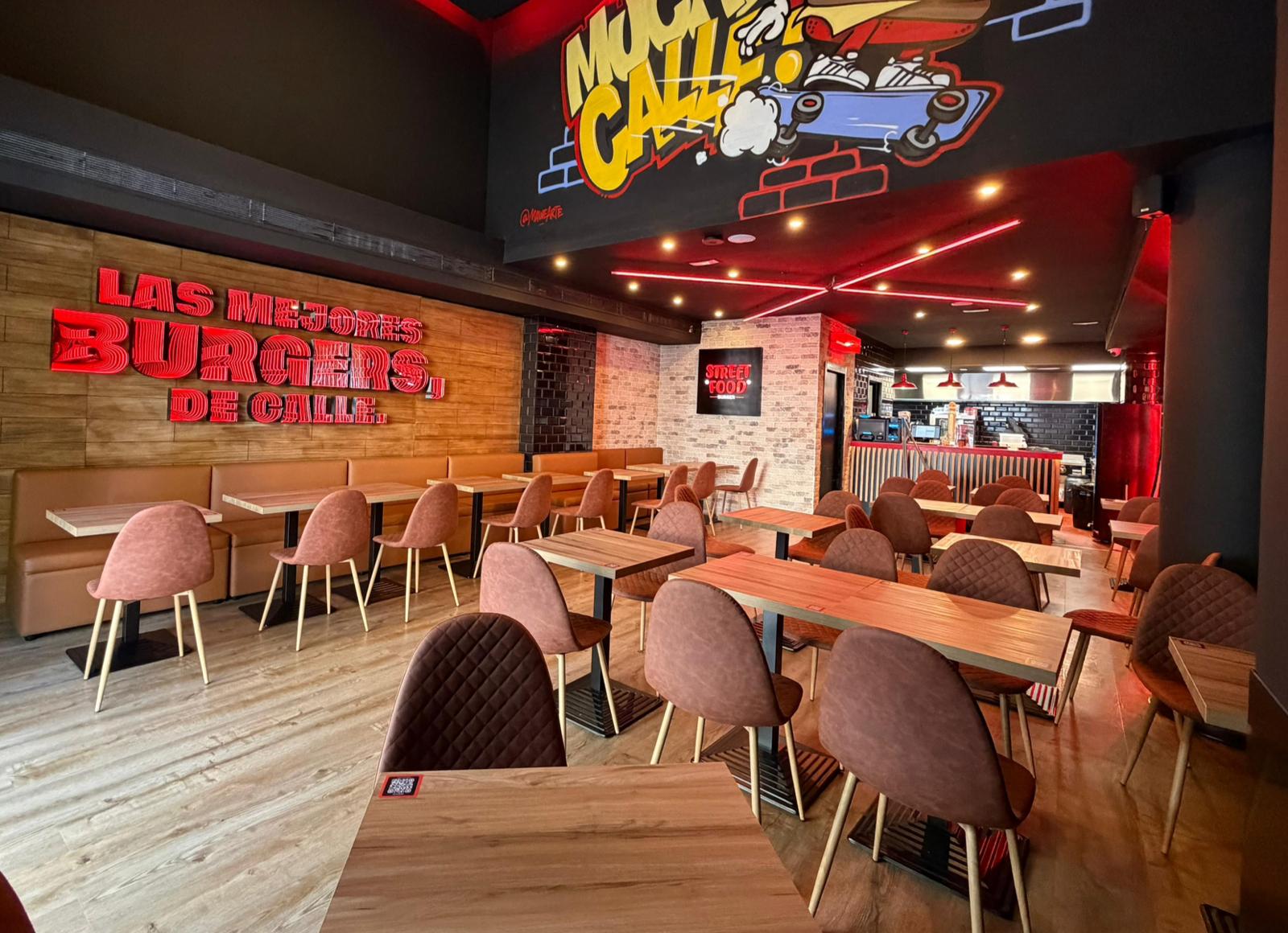 Interior de Street Food Burger Málaga Centro, con mesas y letreros rojos